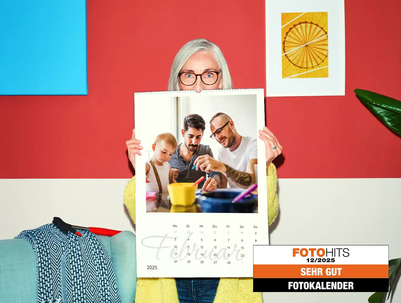 Eine weißhaarige Frau im gelben Strickmantel hält einen großen Terminkalender vor sich, der zeigt, wie du deinen Fotokalender selbst gestalten könntest.