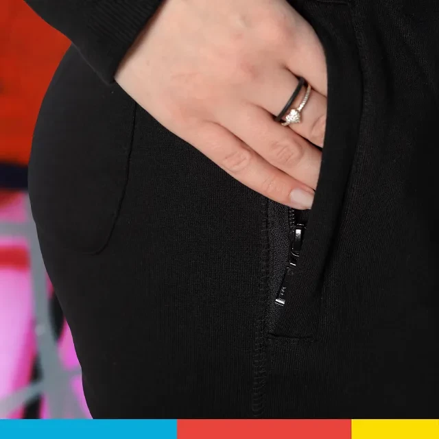 Die schwarze Jogging-Hose mit ORWO-Logo am unteren rechten Bein, ist mit elastischen Taschen ausgestattet und kann mit Hilfe eines Reißverschlusses verschlossen werden.