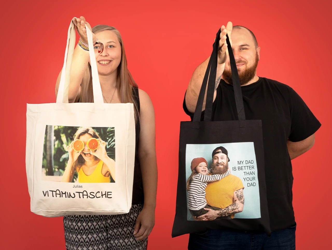 Sie präsentiert eine große Einkaufstasche in heller Leinenoptik, er zeigt einen schwarzen Stoffbeutel mit langen Henkeln – beide personalisierbar.