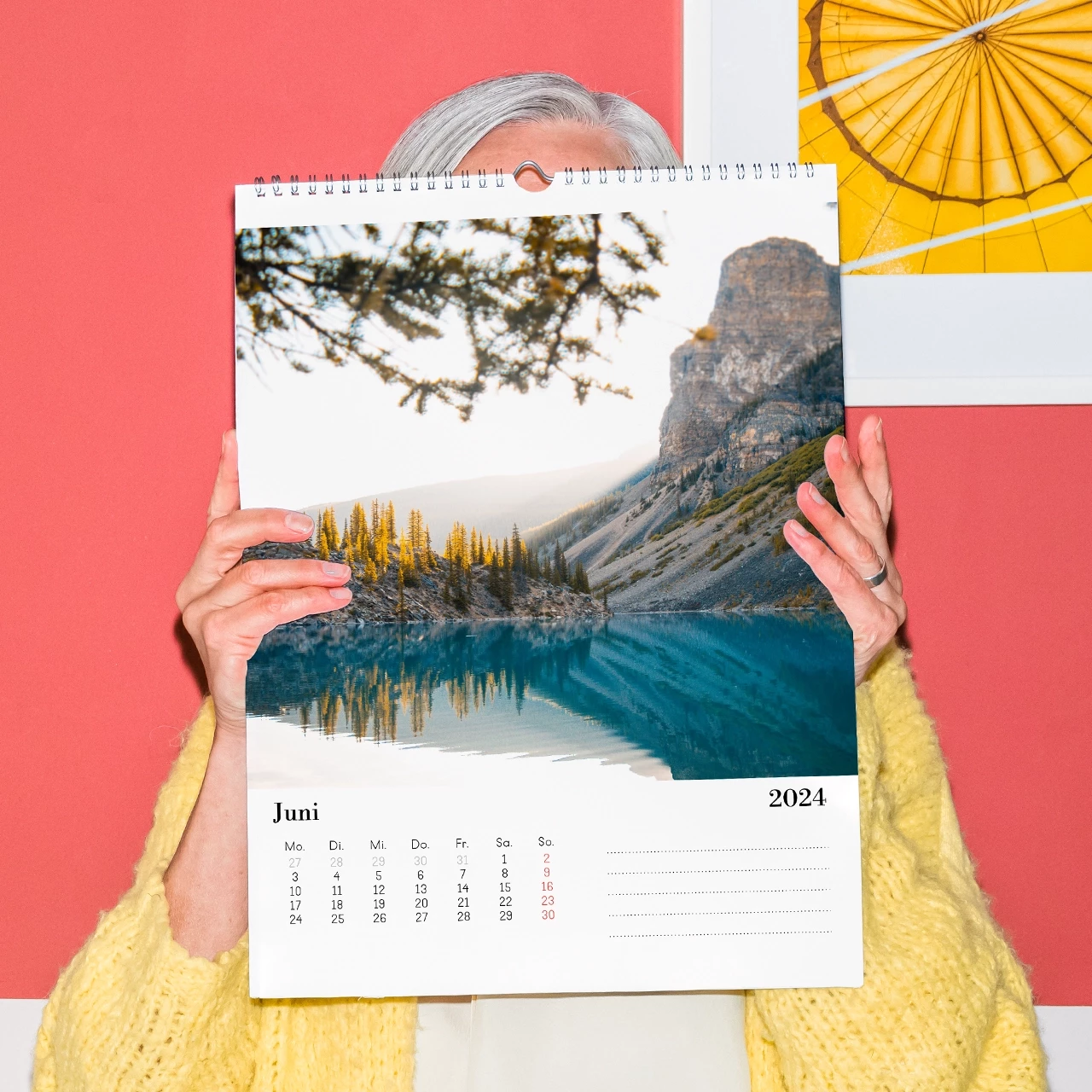 Eine ältere Dame hält einen Aktionskalender vor sich, um die herausragende Qualität und die Art und Weise der Bedruckung des günstigen Fotokalenders zu zeigen.