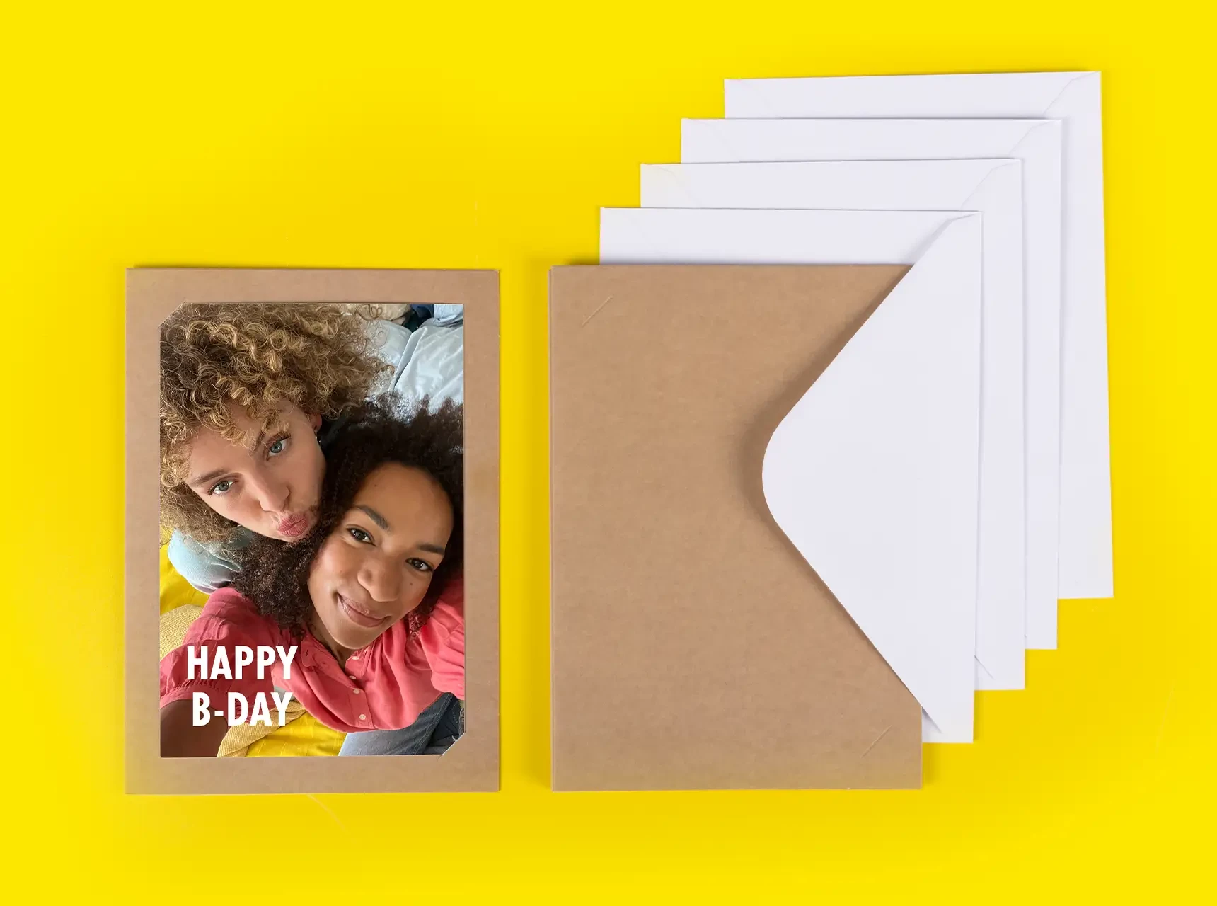 Kraftpapier-Foto-Klappkarte mit eingestecktem Bild von Freundinnen, daneben weißer Briefumschlag.