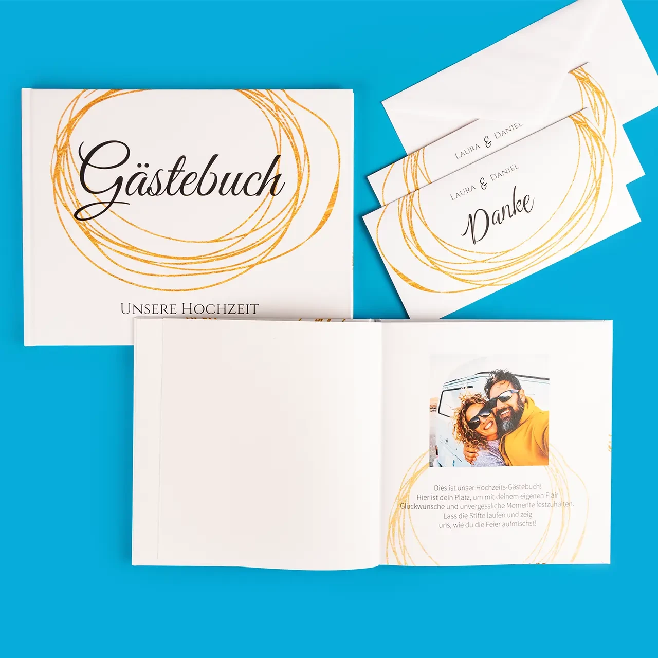 Zu sehen ist ein Gästebuch mit goldenen Designelementen für die Hochzeit, daneben liegen Dankeskarten im selben Stil. Genau so geht Hochzeit mit Stil.