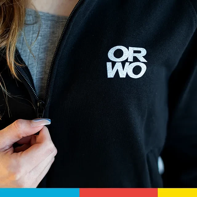 Sweatjacke mit ORWO-Print, Reißverschluss, Bio-Baumwolle Die ORWO Sweatjacke mit dem kleinen Logo-Print auf der linken Brust ist zu sehen, die gerade von einer Hand via hochwertigen Reißverschluss geöffnet wird.