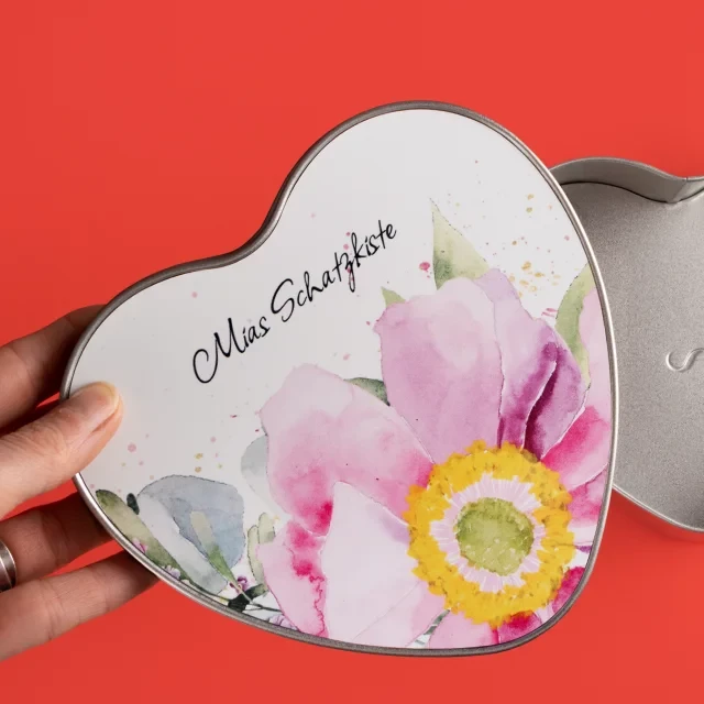 Dose in Herz-Form, mit Aquarell-Blumen-Design. Die Dose ist mit den Worten Mias Schatzkiste beschriftet und gibt eine Idee, wie du deine Dose gestalten könntest.