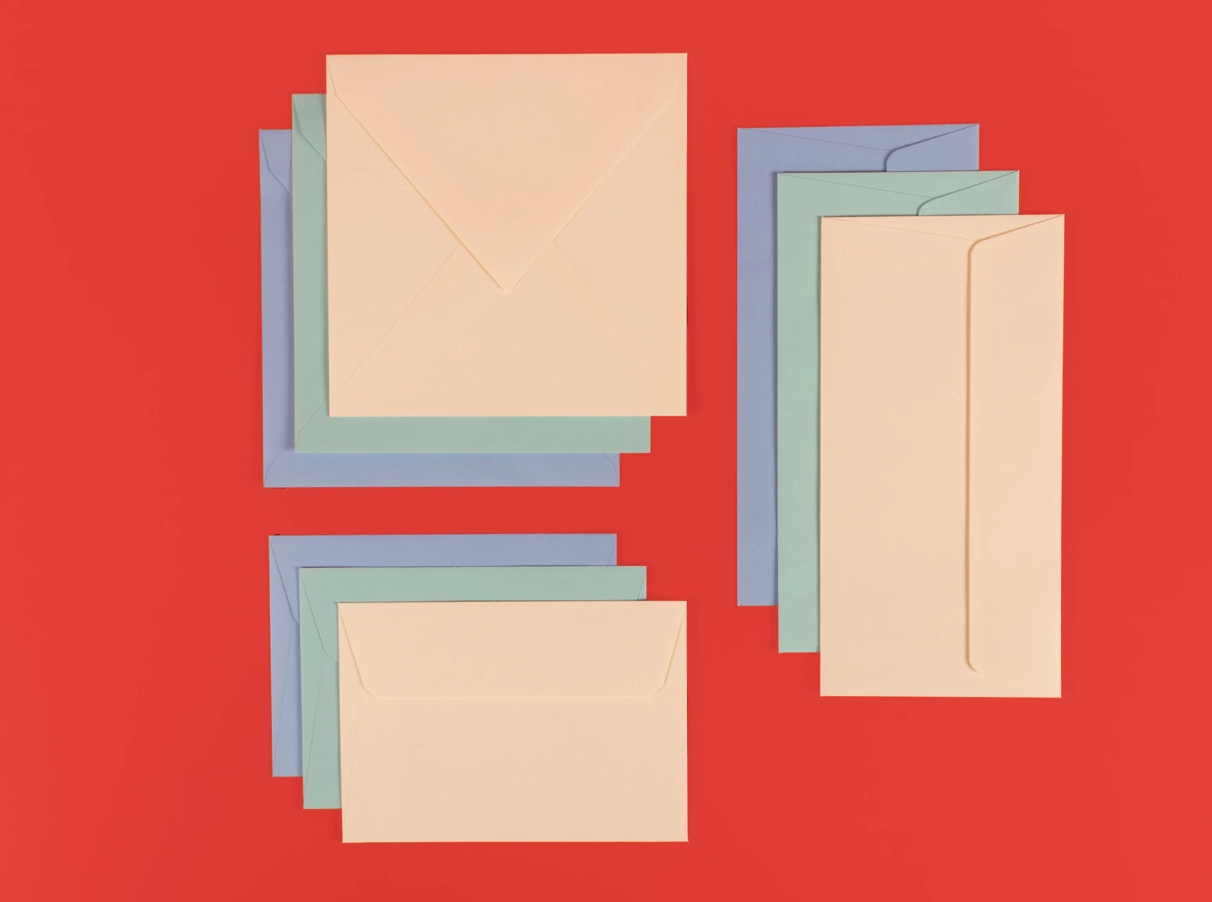 Briefumschläge in den Farben Elfenbein, Himmelblau und Mint, jeweils in den Formaten klassisch, DIN Lang und quadratisch nebeneinander arrangiert.