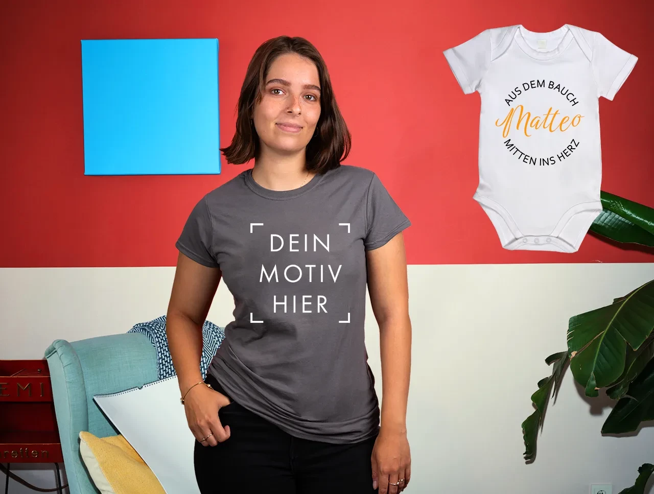 Bekleidung – Kleidung mit Lieblingsmotiven bedrucken und verschenken In einem farbenfrohen Raum zeigt eine junge Frau ein graues T-Shirt mit markiertem Druckbereich. Ein Babybody mit Fotodruck wird daneben gezeigt.