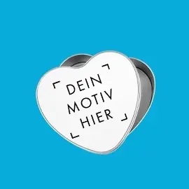 Metalldose in Herzform mit weißem, bedruckbarem Deckel. Der Deckel ist mit einem Platzhaltermotiv versehen. Präsentiert vor blauem Hintergrund