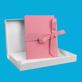 myLeporello in Rosa – zart & liebevoll verpackt Rosa Leinen-mit-Schleife-Version des myLeporellos in weißer Geschenkverpackung. Gefaltet dargestellt vor blauem Hintergrund.