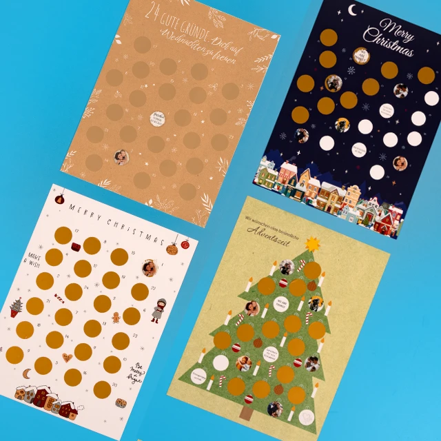 Adventskalender zum Rubbeln – Vier Designs bereit für deine Fotos Vier Rubbel Adventskalender liegen auf blauem Hintergrund. Gestalte deine besondere Adventszeit