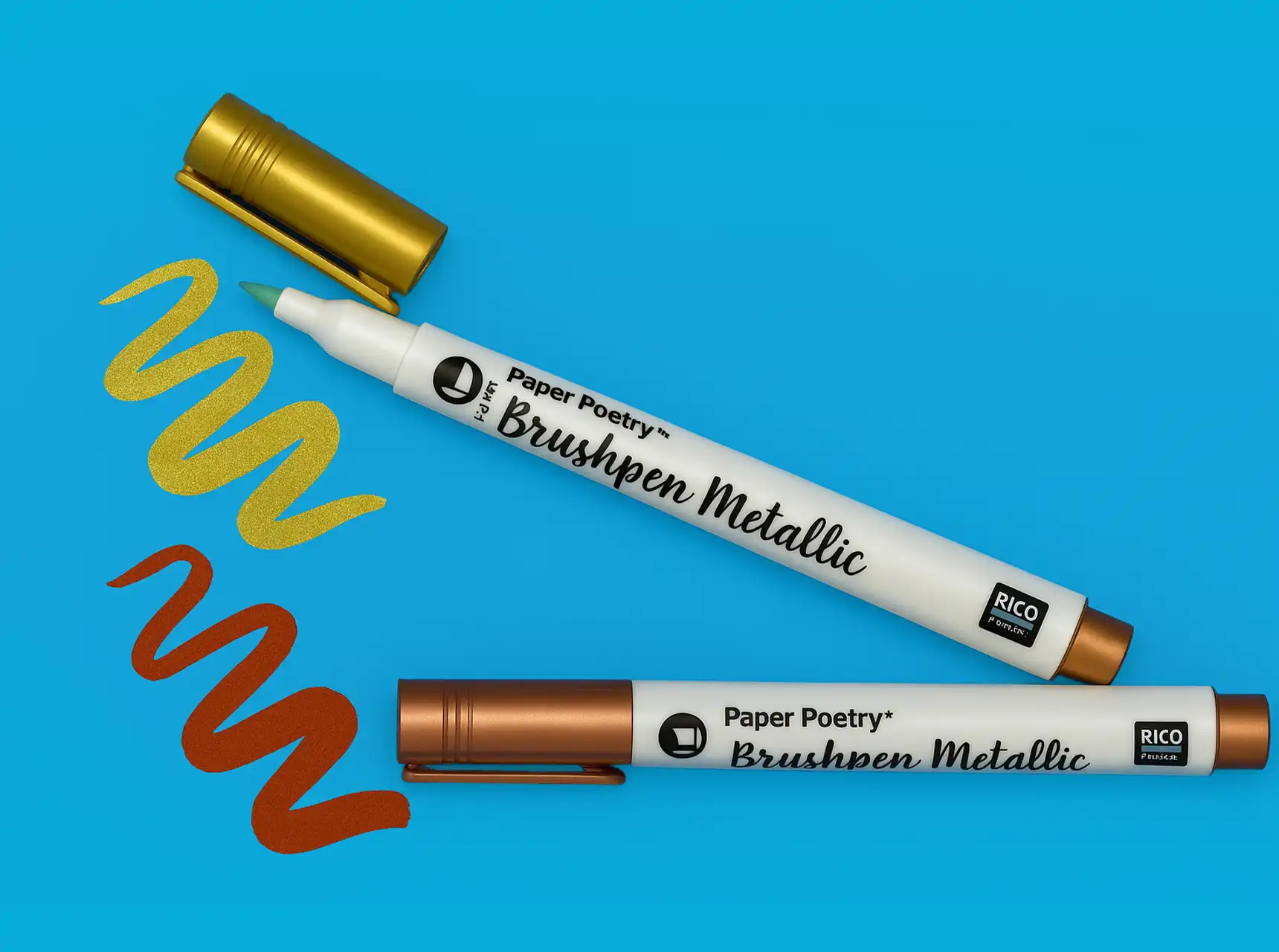 Zwei Brushpens in Metallic-Farben auf blauem Hintergrund, mit goldenen und kupferfarbenen Pinselstrichen daneben.