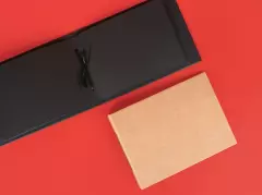Kleines Fotoalbum – schwarze und braune Varianten zum kreativen Gestalten und Einkleben Ein aufgeschlagenes schwarzes und ein geschlossenes hellbraunes Fotoalbum aus Kraftpapier liegen nebeneinander. Beide eignen sich zum Einkleben von Bildern.