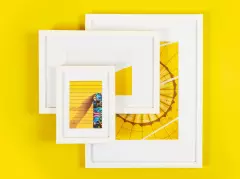 Bilderrahmen – moderne weiße Rahmen in verschiedenen Größen für deine Fotos Drei weiße Bilderrahmen in verschiedenen Größen liegen auf einem gelben Hintergrund. Die gelb getönten Fotos in den Rahmen passen sich farblich an.