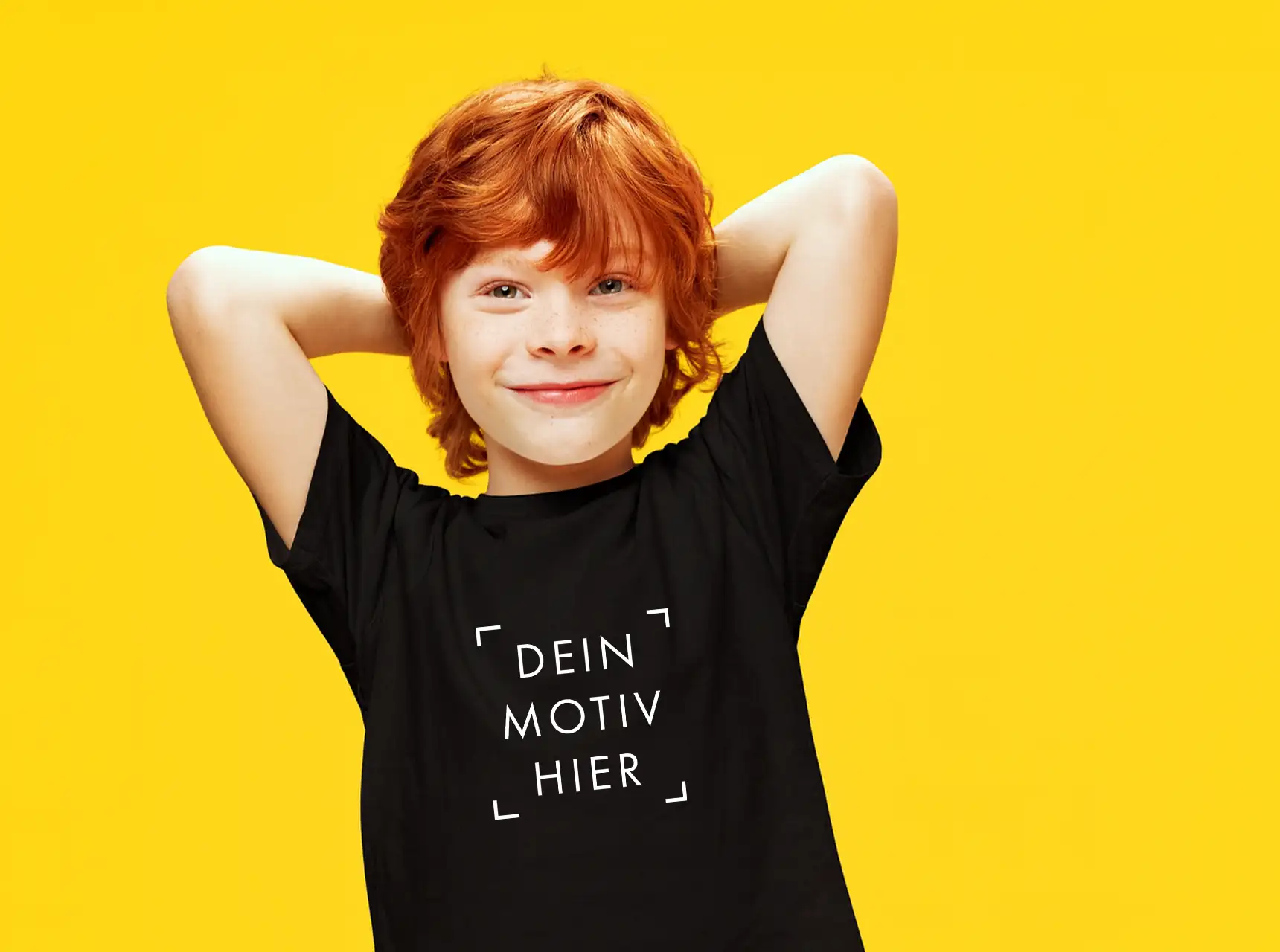 Kindershirts bedrucken – fröhlicher Junge trägt individuelles schwarzes T-Shirt mit eigenem Motiv auf gelbem Hintergrund.