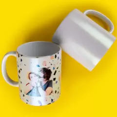 Tasse mit Perlmutteffekt, individuell bedruckbar Zwei Perlmutt-Glitzertassen auf gelbem Hintergrund. Eine Tasse ist mit Foto gestaltet, die andere ist weiß.