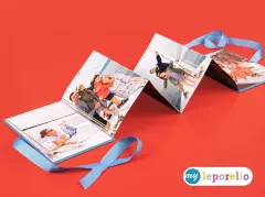 Azurblaues Leporello, das mit mehreren Fotos bestückt wurde, liegt ausgebreitet auf rotem Untergrund und präsentiert die volle Pracht des Leporellos mit drei Doppelseiten.