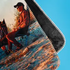 Fotodecke mit Outdoor-Motiv: Person sitzt beim Camping auf individuell bedruckter Decke.