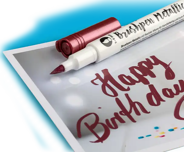 Metallic Brushpen in Kupfer, mit handgeschriebener Aufschrift „Happy Birthday“ auf einer Karte.