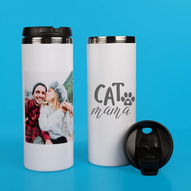 Zwei weiße Thermobecher auf blauem Hintergrund – einer mit Foto eines Paares beim Winterausflug, der andere mit der gravierten Aufschrift „Cat mama“ und schwarzem Deckel daneben.