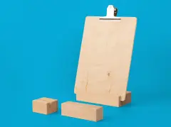 Zwei schlichte Fotohalter aus hellem Holz mit Schlitz für Bilder sowie ein Fotohalter mit Klemmbrett-Funktion auf blauem Hintergrund